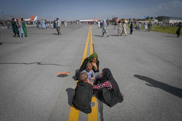 Women and children sitting on the tarmac at Kabul’s international airport on Monday. The airport was overrun with people seeking to leave the country.