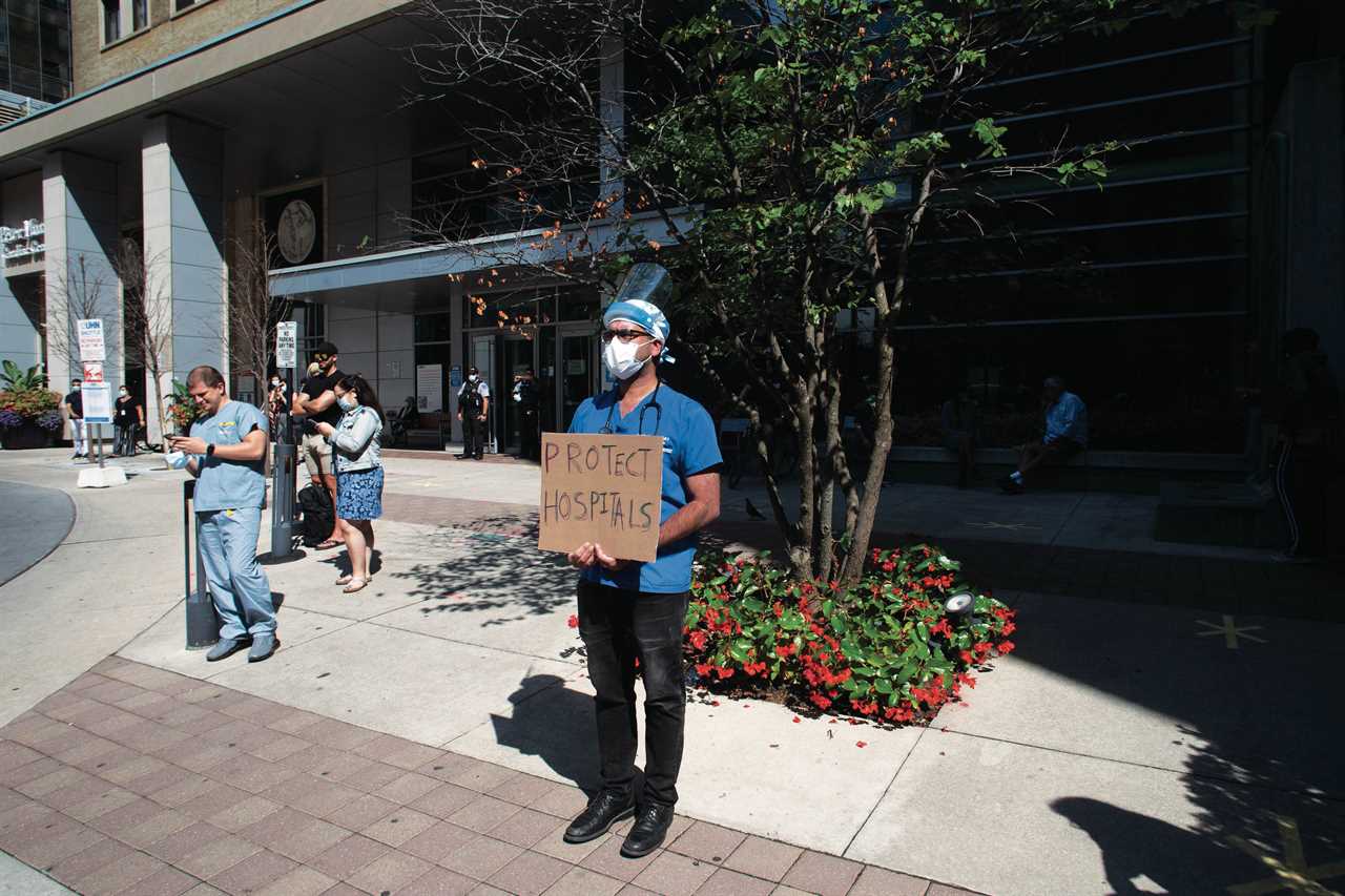 A healthcare worker holds a sign as demonstrators gather outside Toronto General Hospital on Monday, September 13, 2021, to protest against COVID-19 vaccines, COVID-19 vaccine passports and COVID-19 related restrictions. (Chris Young/CP)